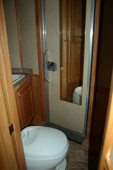 Bathroom with sink/vanity, closet, toilet & shower. Also walk-thru door to stall area